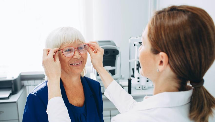 an elderly woman tries on new glasses as age affects her vision